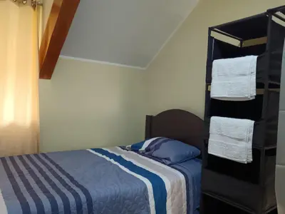 a bedroom with a bed and a shelf with towels at La Casa de Anni Departamento 2 in Oxapampa