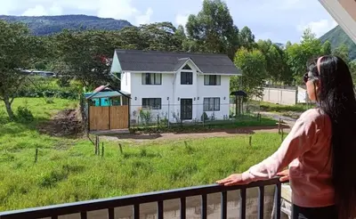 a woman standing on a balcony looking out at a house at La Casa de Anni Departamento 2 in Oxapampa