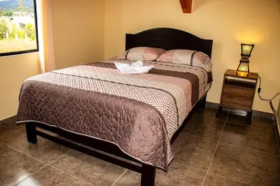a bedroom with a bed with a brown comforter at La Casa de Anni Departamento 2 in Oxapampa