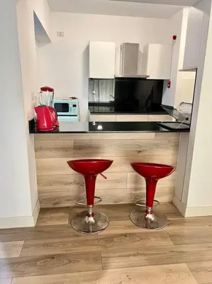 a kitchen with two red stools in front of a counter at Amplio, Bonito , Silencioso y céntrico en Miraflores in Lima