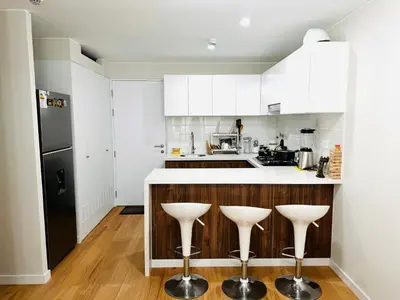 a kitchen with white cabinets and white stools at Alojamiento Mama Ocllo in Lima