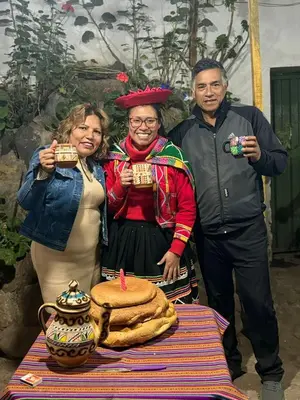 a group of three people standing next to a table with a cake at Hospedaje Rosita INN in Cusco