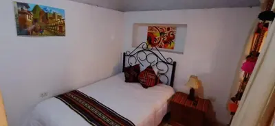 a small bedroom with a bed with white sheets at Hospedaje Rosita INN in Cusco