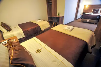 a hotel room with three beds and a desk at San Francisco Pardo Hotel in Cusco