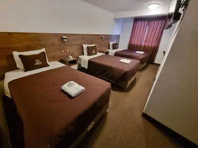 a hotel room with two beds and a chair at San Francisco Pardo Hotel in Cusco