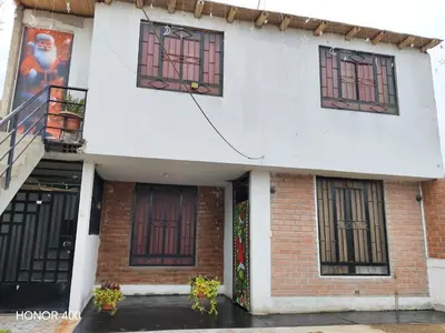 a white building with windows on a rainy street at Casita de camucha in Chincha Baja