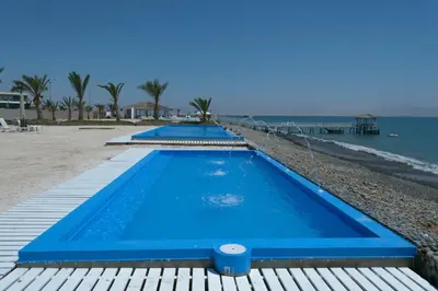 a row of blue swimming pools on the beach at Apartamento Frente a Islas Ballestas in Paracas