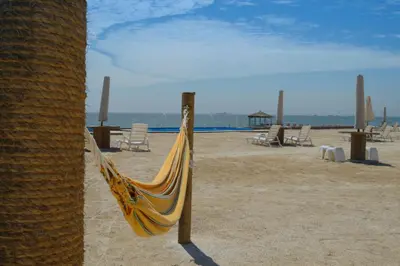 a yellow hammock on a beach with chairs at Apartamento Frente a Islas Ballestas in Paracas