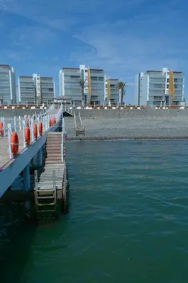 a dock with orange barrels in the water next to buildings at Apartamento Frente a Islas Ballestas in Paracas