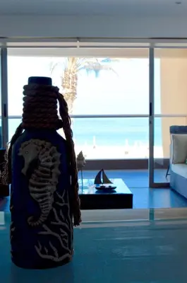 a bottle on the floor of a living room with a view of the beach at Apartamento Frente a Islas Ballestas in Paracas