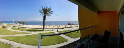 a balcony with a view of the ocean and a palm tree at Apartamento Frente a Islas Ballestas in Paracas