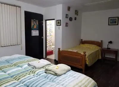 a bedroom with three beds and a bedskirts at Hospedaje interno surco in Lima