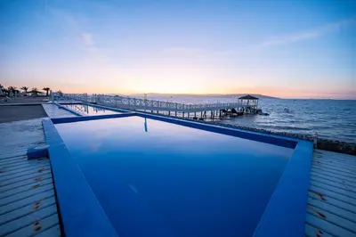 a swimming pool next to the ocean with a pier at Sotavento Beach Homes by Vibrant in Paracas