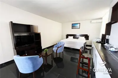 a hotel room with a bed and a table and chairs at Qallwa Chincha in Chincha Alta