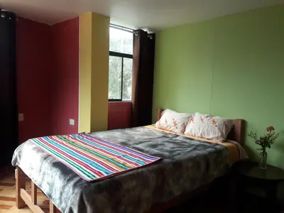 a bedroom with a bed with green walls and a window at Hostal El Viajero in Surcubamba