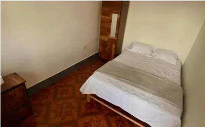 a bedroom with a bed with white sheets and pillows at Casa Límaco in Ayacucho