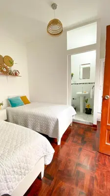 a bedroom with two beds and a bathroom with a sink at 2 beds with garden view and terrace in Lima