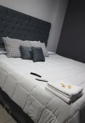 a large white bed with two towels and a remote control on it at Casa sabina aeropuerto plus in Lima