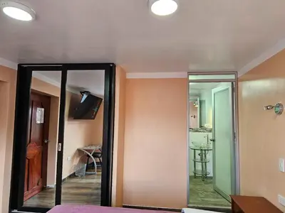 a bedroom with a mirror and a room with a table at Casa Rustica Hostal Paqcha in Cusco