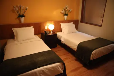 a hotel room with two beds and a lamp at Park Hotel Lima in Lima