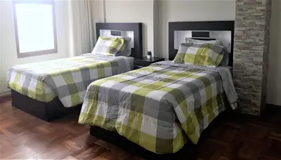 two beds sitting next to each other in a bedroom at Royalty Inn in Lima