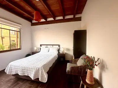 a bedroom with a white bed and a chair at Refugio del Mar Wakama in San Vicente de Cañete
