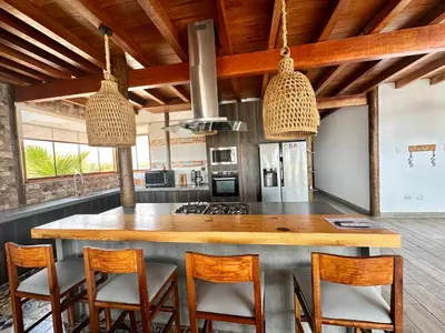 a kitchen with a large wooden island with chairs at Refugio del Mar Wakama in San Vicente de Cañete