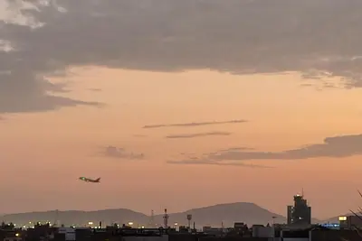 an airplane flying in the sky over a city at Sumaq Apartment Lima Airport in Lima