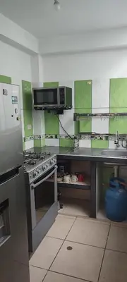 a kitchen with green and white walls and a stove at Sumaq Apartment Lima Airport in Lima