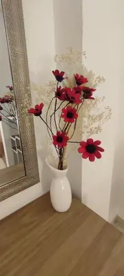 a white vase with red flowers in it on a table at Sumaq Apartment Lima Airport in Lima
