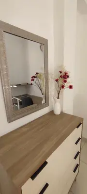 a mirror on top of a dresser with flowers on it at Sumaq Apartment Lima Airport in Lima