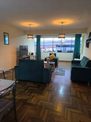 a living room with two blue couches and a large window at Kusi Wasi in Cusco