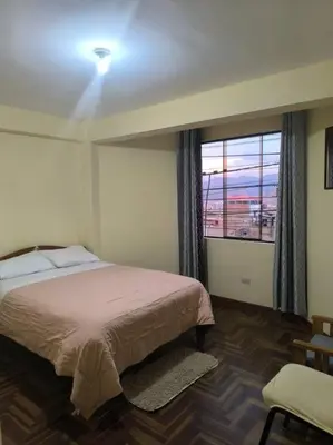 a bedroom with a bed and a large window at Kusi Wasi in Cusco