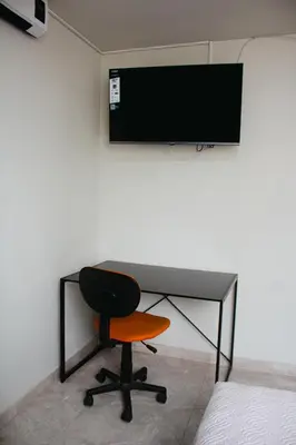 a desk with a chair and a television on a wall at Arleth's hosting in Lima
