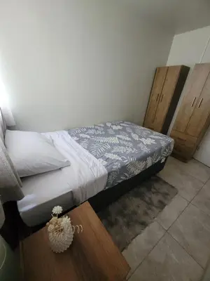 a small bedroom with a bed and wooden cabinets at Arleth's hosting in Lima