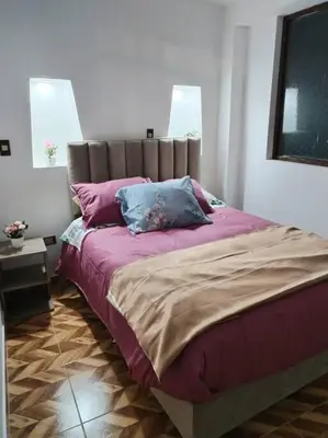 a bedroom with a large bed with purple sheets and pillows at Cori Wasi in Cusco