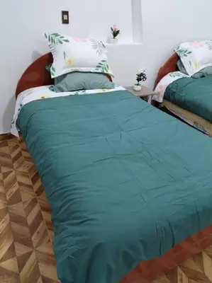 a bed with a green comforter in a room at Cori Wasi in Cusco