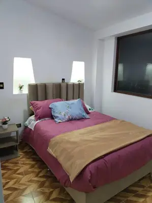 a bedroom with a large bed with purple sheets and pillows at Cori Wasi in Cusco