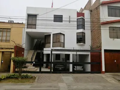 a white building with a black fence in front of it at Departamento con Cochera in Lima