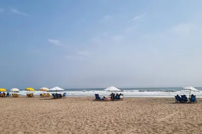 a group of people sitting on a beach with umbrellas at Departamento en playa Arica in Lurín