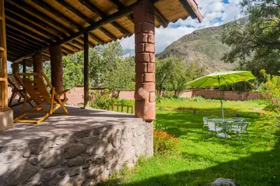 a patio with a green umbrella and a table and chair at Spacious entire house with awesome mountain views in Urubamba
