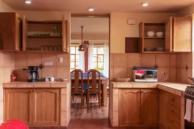 a kitchen with wooden cabinets and a dining room at Spacious entire house with awesome mountain views in Urubamba