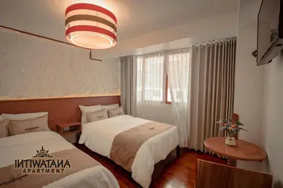 a hotel room with two beds and a large window at Intiwatana Apartment in Cusco