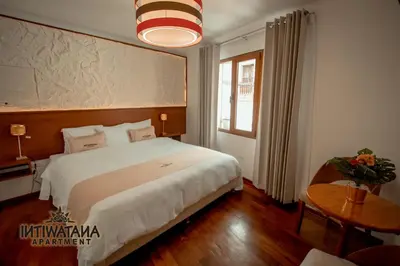 a bedroom with a large bed and a table at Intiwatana Apartment in Cusco