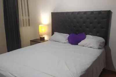 a large bed with a purple heart pillow on it at Apartamento 3Hab Seguridad y Cerca del Aeropuerto in Lima