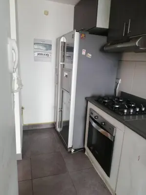 a small kitchen with a stove and a refrigerator at Apartamento 3Hab Seguridad y Cerca del Aeropuerto in Lima