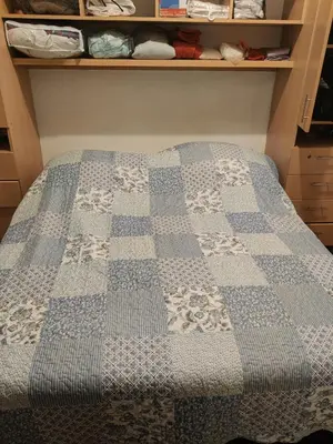 a bed with a blue and white quilt on it at bungalows in Santa Rosa