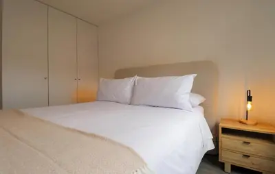 a white bed with white pillows and a night stand at Qoyllur by Wynwood House in Cusco