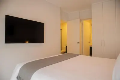 a bedroom with a white bed and a flat screen tv at Vital by Wynwood House in Lima