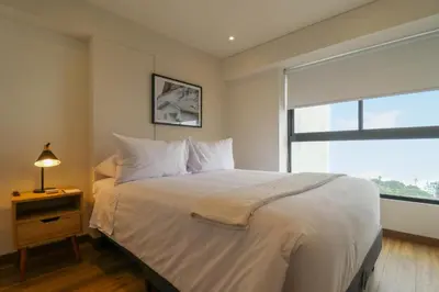 a bedroom with a large white bed with a window at Aquilaria by Wynwood House in Lima